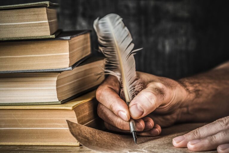 Hombre escribiendo una carta antigua, una pluma antigua, libros y